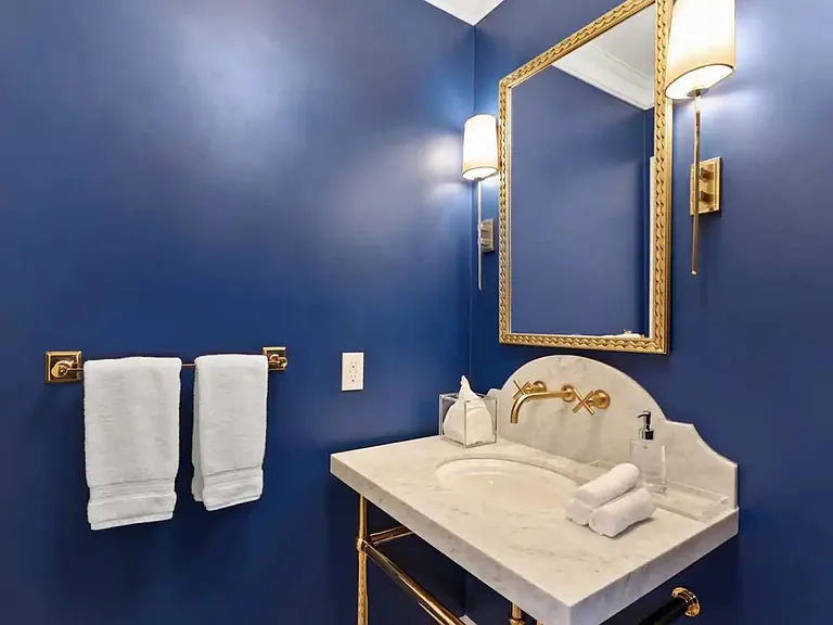 Eye catching royal blue bathroom with bronze accents and furnishings.