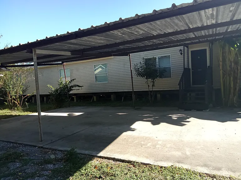 Back view of the double wide mobile home including cover up carport.