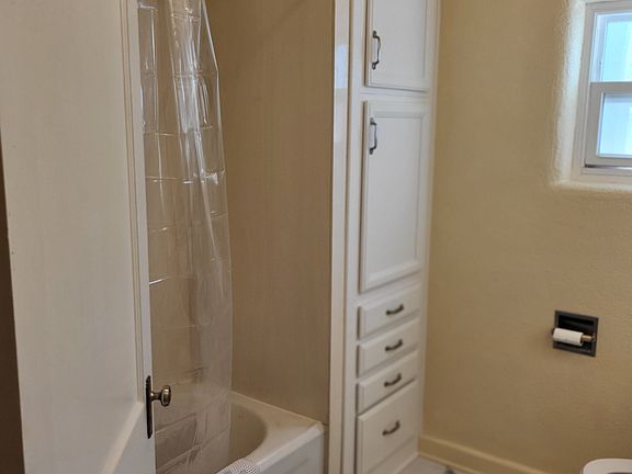 Bathroom view 1 of 2, tub and shower, linen cabinet and drawers.