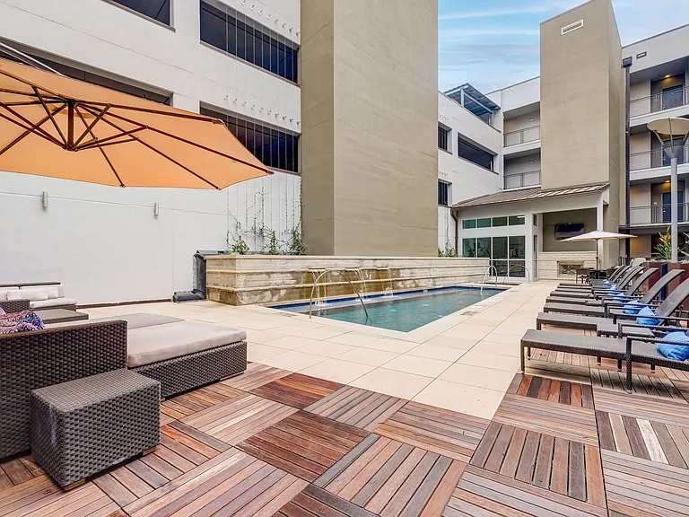 Large sparkling blue pool with a large pool deck and lounge chairs