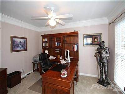 Freshly painted first floor study with french doors, crown molding, ceiling fan & large window with plantation blinds.