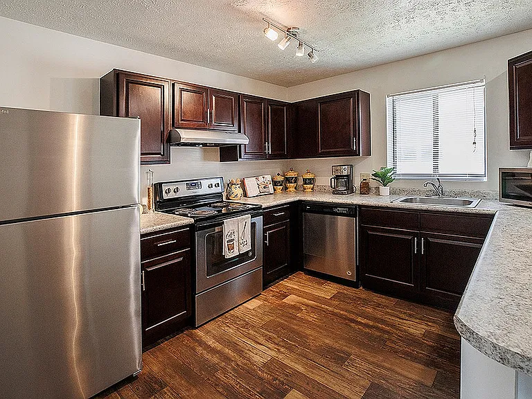Modern kitchen with sleek stainless steel appliances, rich wooden cabinetry, and elegant countertops, offering a warm and inviting atmosphere.