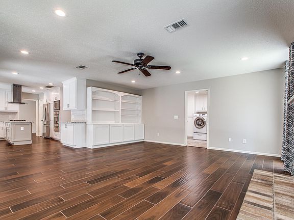 This view of the family room shows off the beautiful tile floors, built-in bookcases, and entry into the oversized laundry room (washer/dryer and refrigerators stay during the lease).