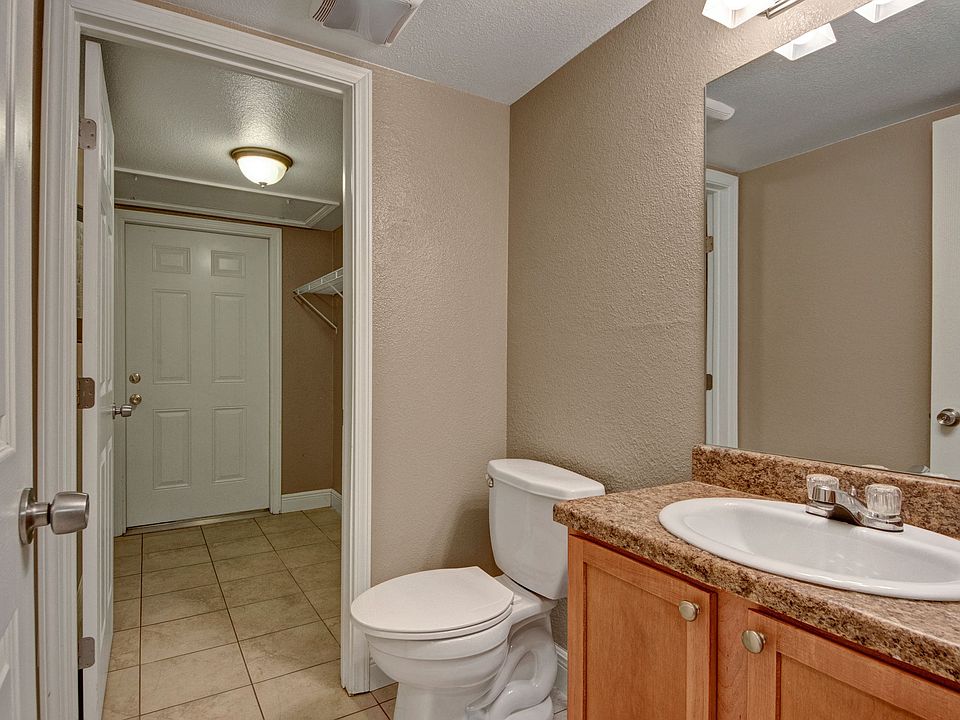 A bathroom with a granite countertop and wide mirror above the sink