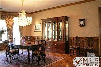 Very large formal dining room featuring oak wainscoting and a crystal chandelier and leaded glass windows and custom draperies.