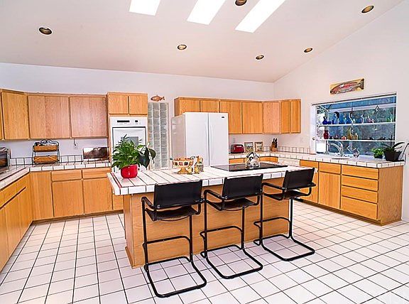 The island kitchen boasts vaulted ceilings with recessed lighting, sky lights, electric oven and range.