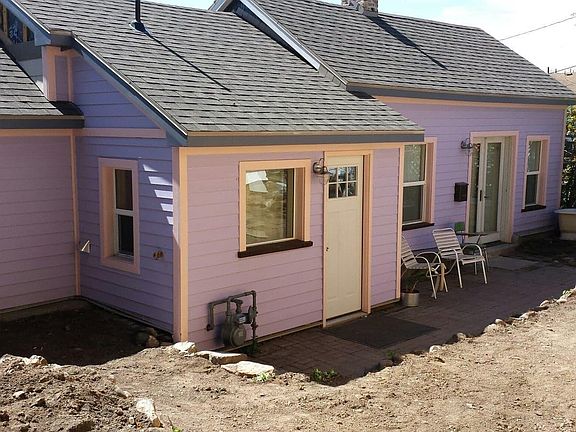Front of Cottage showing brick patio and river rock retaining walls with planting areas.