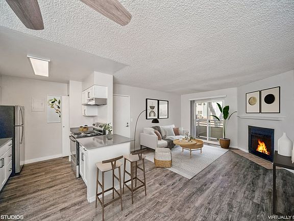 Open living area with wood-style floors, a breakfast bar, and private balcony access.