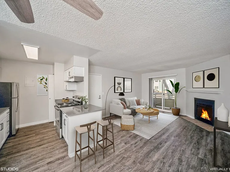 Open living area with wood-style floors, a breakfast bar, and private balcony access.