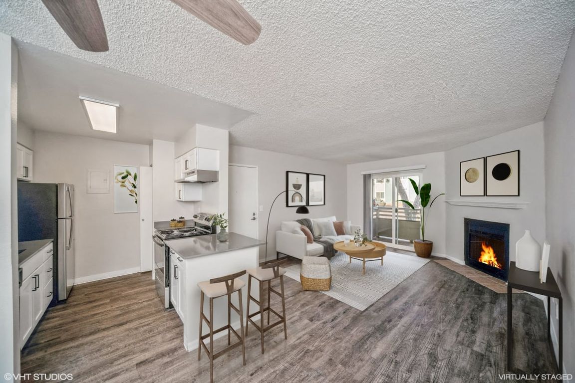 Open living area with wood-style floors, a breakfast bar, and private balcony access.