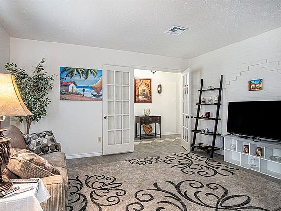Formal Living Room Features a Painted Brick Accent Wall and Double French Doors to Foyer