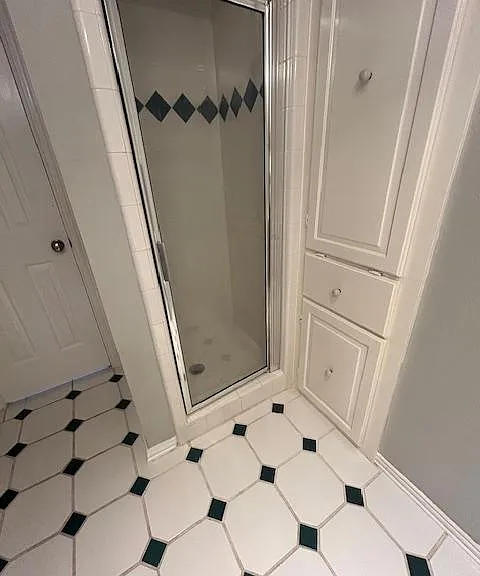 Shared bath has cabinetry for storage and a step-in shower.