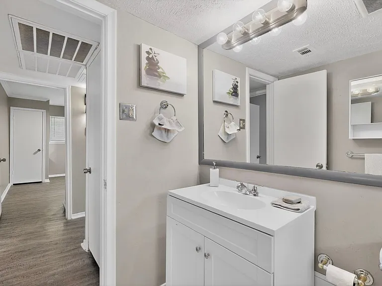 A bright bathroom featuring a vanity with a wide mirror