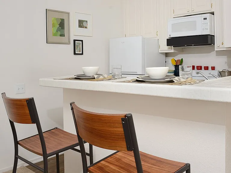 Classic Package I kitchen with white appliances, white tile countertops, white cabinetry, and hard surface flooring