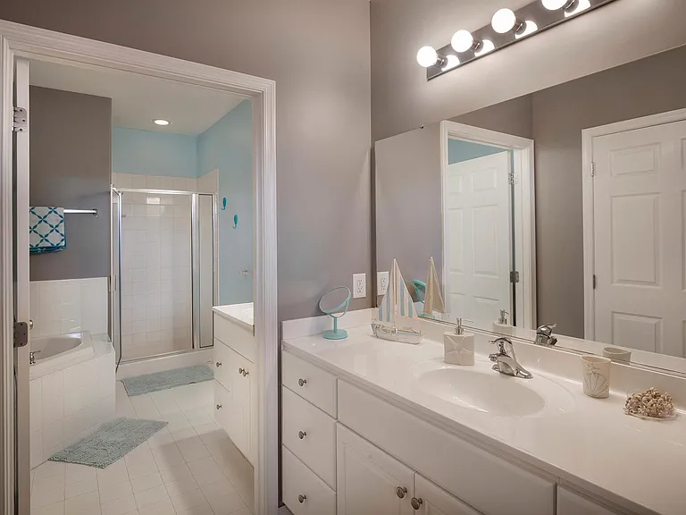 master bathroom with sink, soaking tub and additional sink and mirror outside of the bathroom