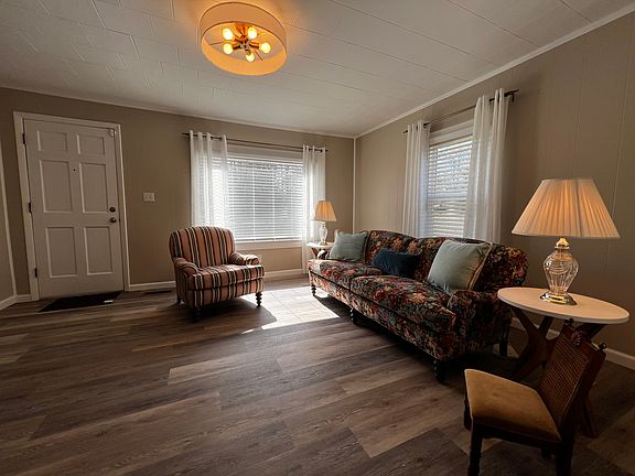 Huge Family Room with wood-look flooring and lots of natural light from the picture window. Includes sofa, chair, end tables, lamps, Smart/Roku 40" TV and entertainment console.