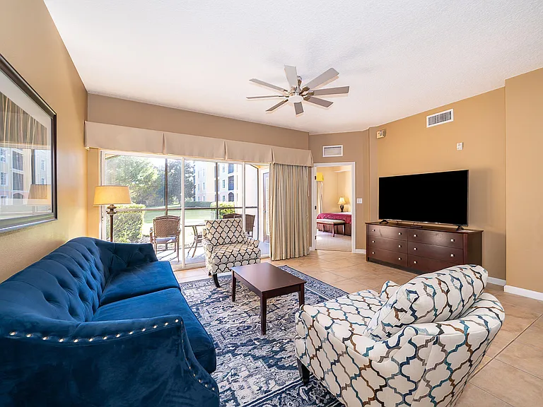 Open living area with seating, large TV console, and sliding doors leading to a furnished patio.