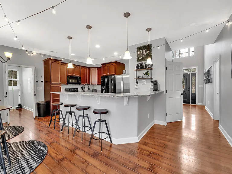 Open kitchen with breakfast bar seating, ample cabinetry, and stainless-steel appliances, flowing into the main living area.