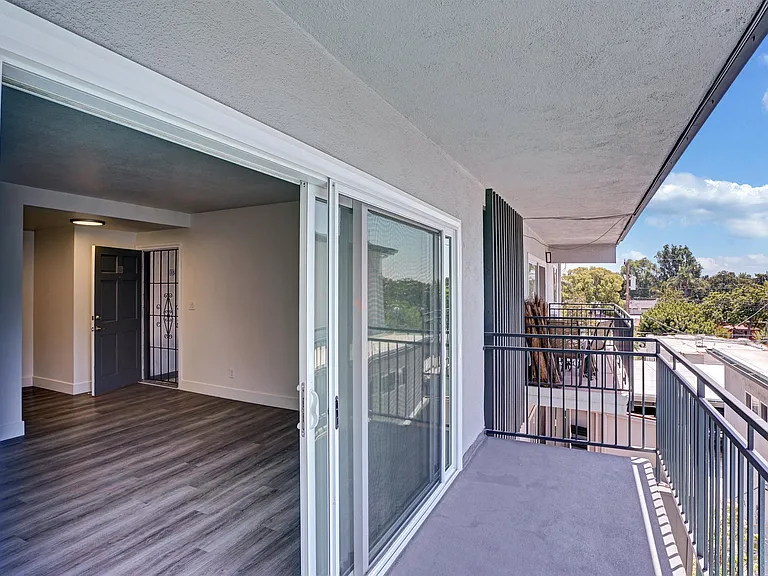 A second floor balcony with a glass door leading to a room.