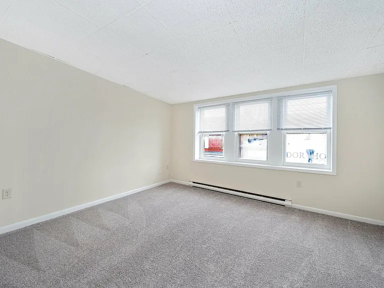 Experience the airy ambiance of this modern apartment with expansive windows and soft carpeting.