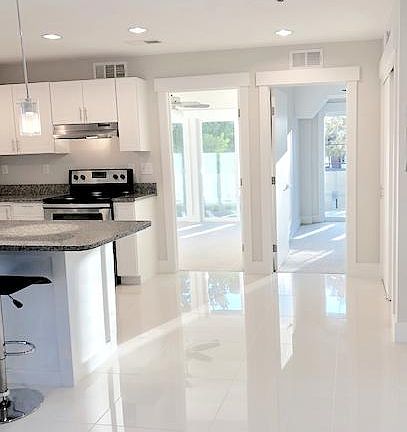 The Kay: 2BD / 1BA. Ultra-modern white tile. Shown with kitchen island.