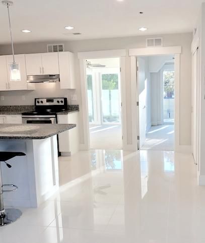 The Kay: 2BD / 1BA. Ultra-modern white tile. Shown with kitchen island.