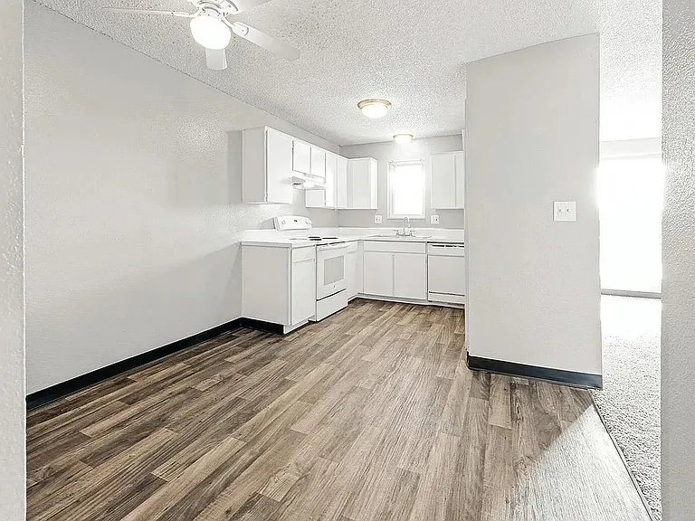 Bright and modern white kitchen with sleek cabinetry and elegant wood flooring.