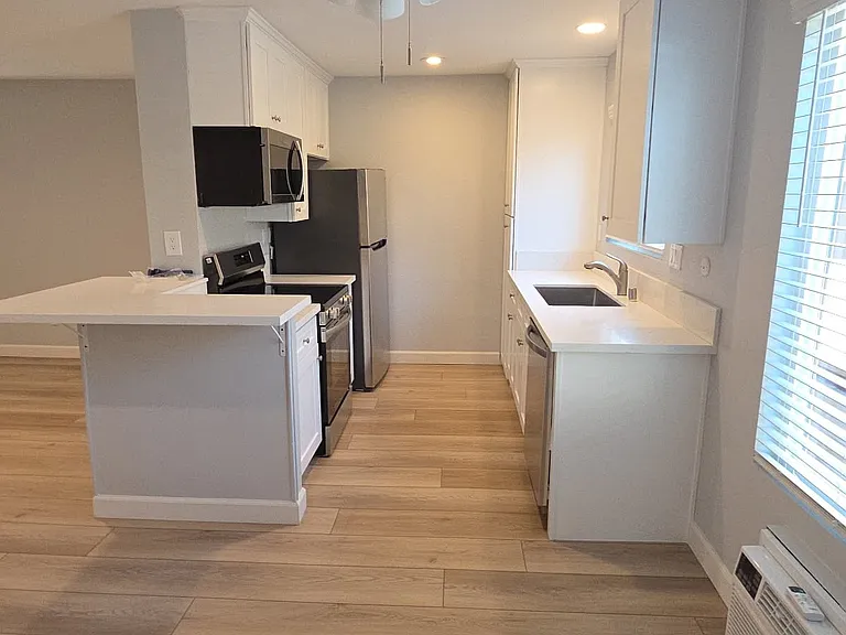 Modern kitchen with brand new electric oven/stovetop, dishwasher, refrigerator, and microwave.