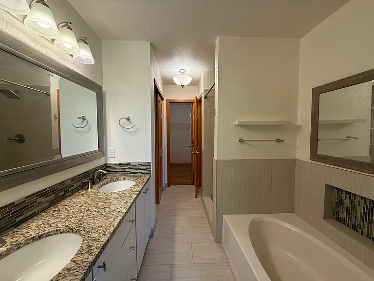Beautifully remodeled spa-inspired bathroom featuring dual vanities, a soaking tub, and a walk-in shower