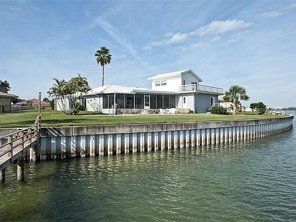 View from the end of the dock showing the back of the home with its oversized back yard and RipRap seawall