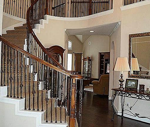 Stunning entry has curved wrought iron staircase, arches, niches & awesome light fixture!