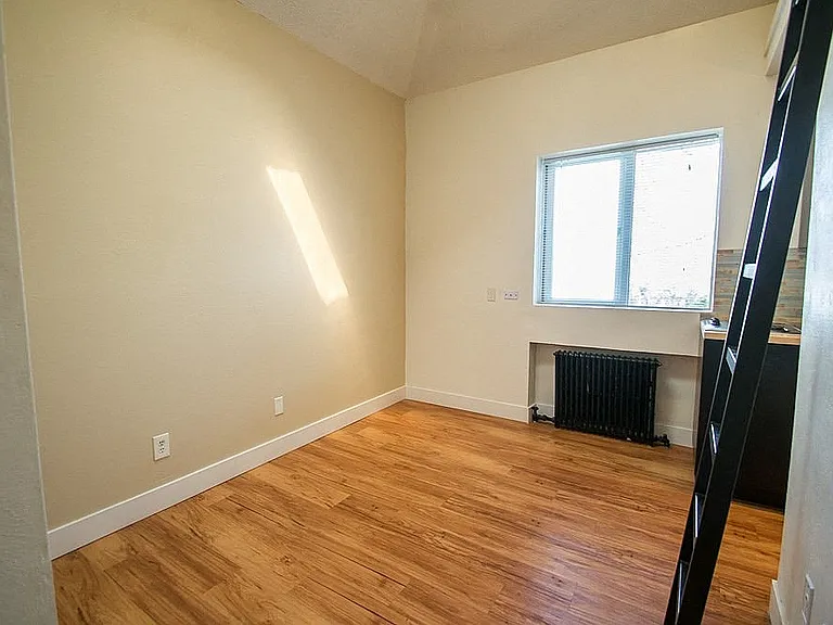 Bright and cozy room with stylish wooden flooring and a large window inviting natural light.