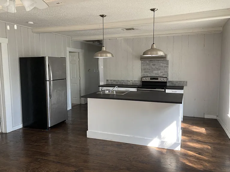 Kitchen with island, fridge, and stove all included. Hardwood flooring throughout living areas