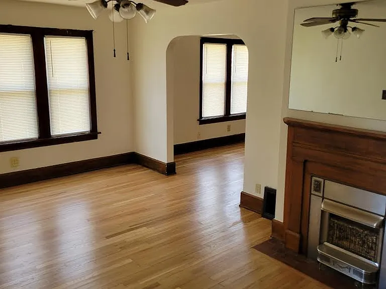 Livingroom leading to dining room with fireplace, mirror, ceiling fan, and new windows.