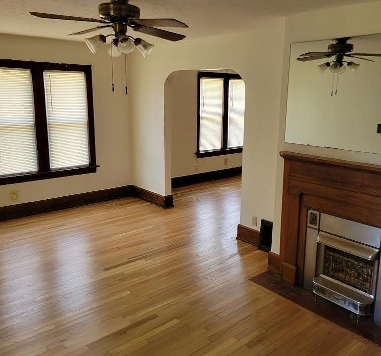 Livingroom leading to dining room with fireplace, mirror, ceiling fan, and new windows.