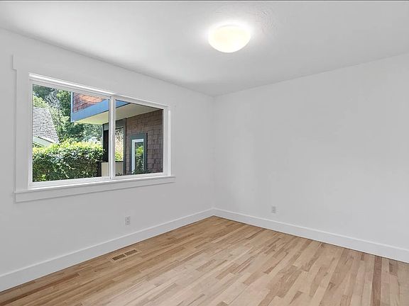Late morning light floods bedroom that looks out small leafy garden.