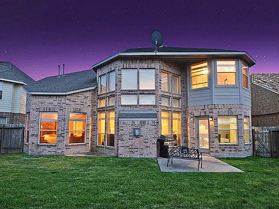 View from the back of the home accents all of the large windows looking in from the lush green lawn.