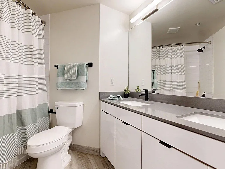 Apartment Bathroom with large soaking tub, vanity mirror and Wood-Style Flooring.