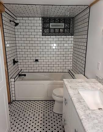 Marble vanity, retro black and white floor tile, subway tile tub surrounding a jacuzzi tub.