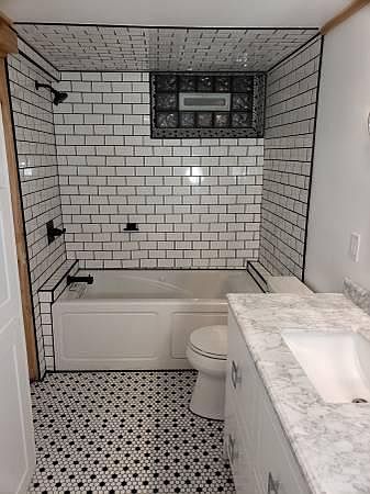 Marble vanity, retro black and white floor tile, subway tile tub surrounding a jacuzzi tub.