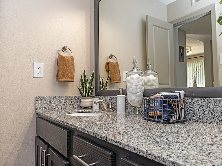 Bright bathroom with granite counters and large mirror