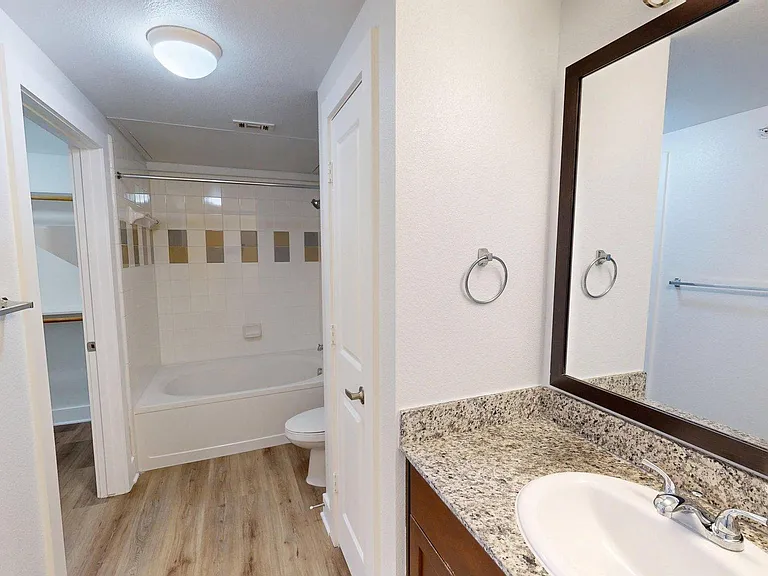 Apartment bathroom with soaking tub and wood style floor.