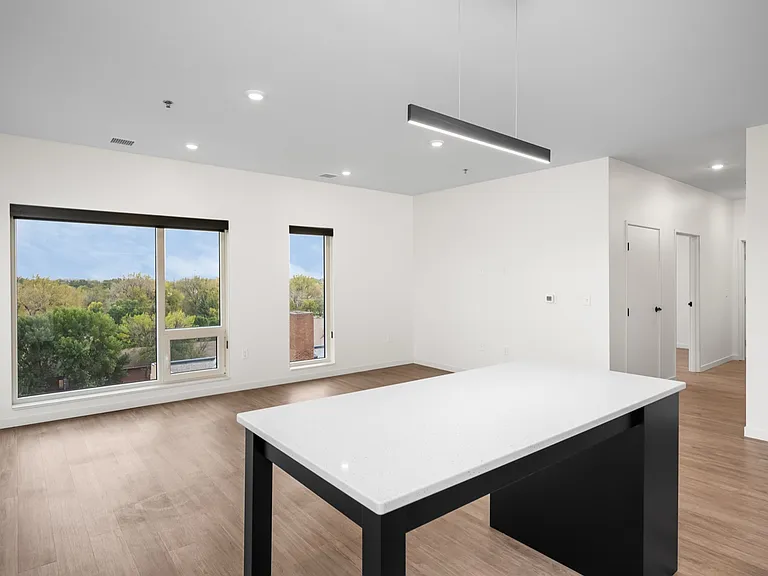 Bright and airy living space featuring large windows with scenic views, modern lighting, and a sleek countertop in a stylish open-plan area. Bright and airy living space featuring large windows with scenic views, modern lighting, and a sleek countertop in
