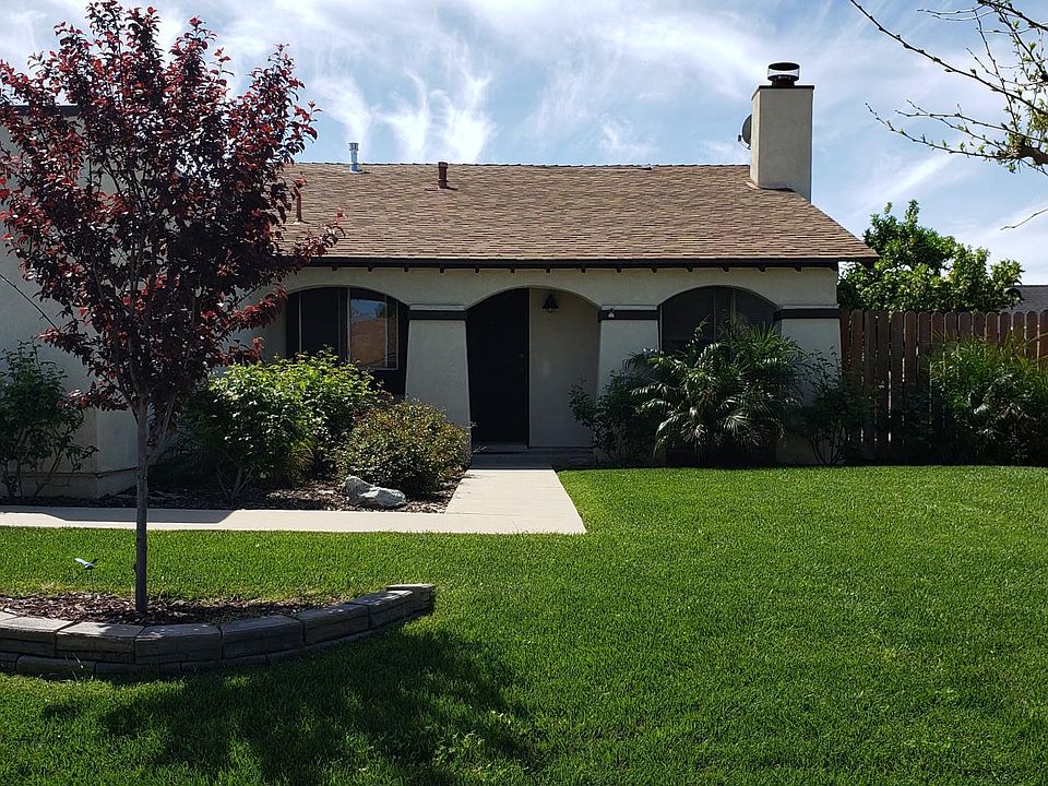 Front yard view with landscaped yard, roses, dwarf palms and shade trees.