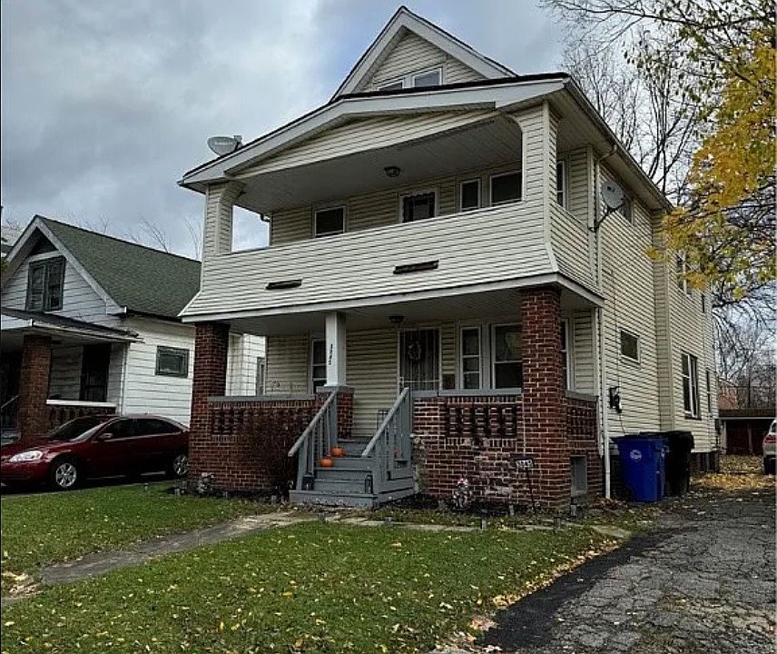 View of front of property with brick siding, a front yard, and covered porch