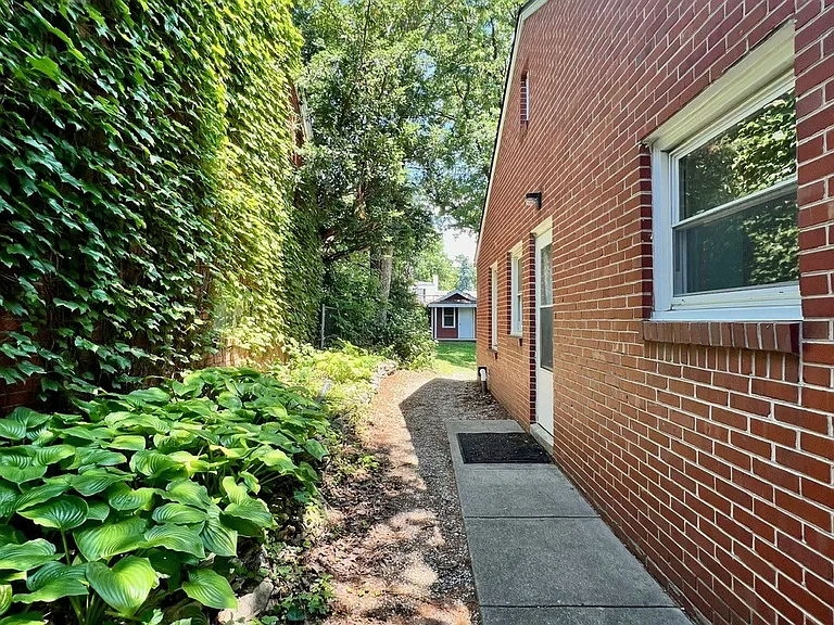 Greenery-lined walkway from front of house to backyard includes separate side entry to house.