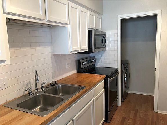 Hardwood floors and butcher block warm the white and modern kitchen.