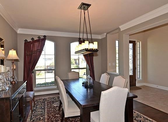 Formal dining boasts of hand scraped, wide plank hardwood flooring, custom window treatments, crown 