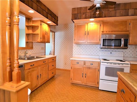 Handmade Oak Cabinets surround the new stainless Whirlpool dishwasher and microwave. A cute little window that looks out to the 
