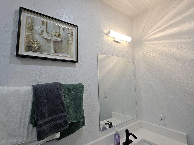 Bathroom 2 vanity area with a wide countertop, wall mirror, and towel bar for convenient daily use.